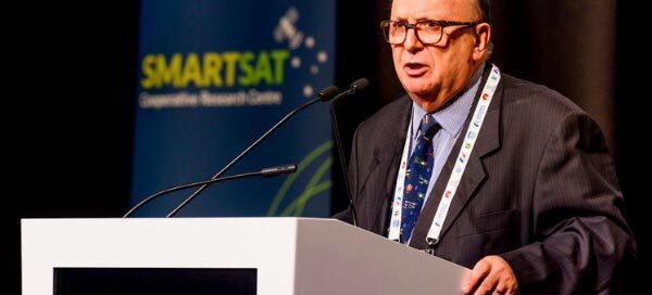 Man speaking at 8th space forum in front of SmartSat banner