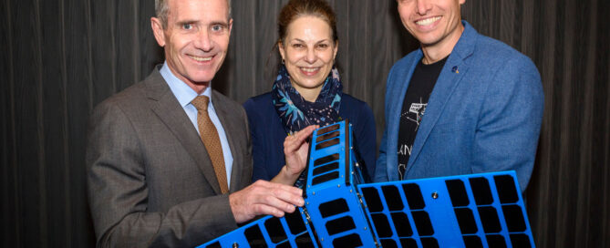 Two men and one woman holding a satellite demo